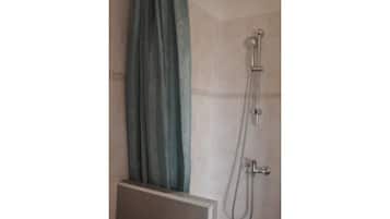 A shower with a curtain, a handheld showerhead, and a wall-mounted faucet.