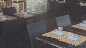 A rustic interior with wooden walls, stone accents, and a bar area. Tables and chairs are arranged for dining. - Résidence Maora Village (Bonifacio)
