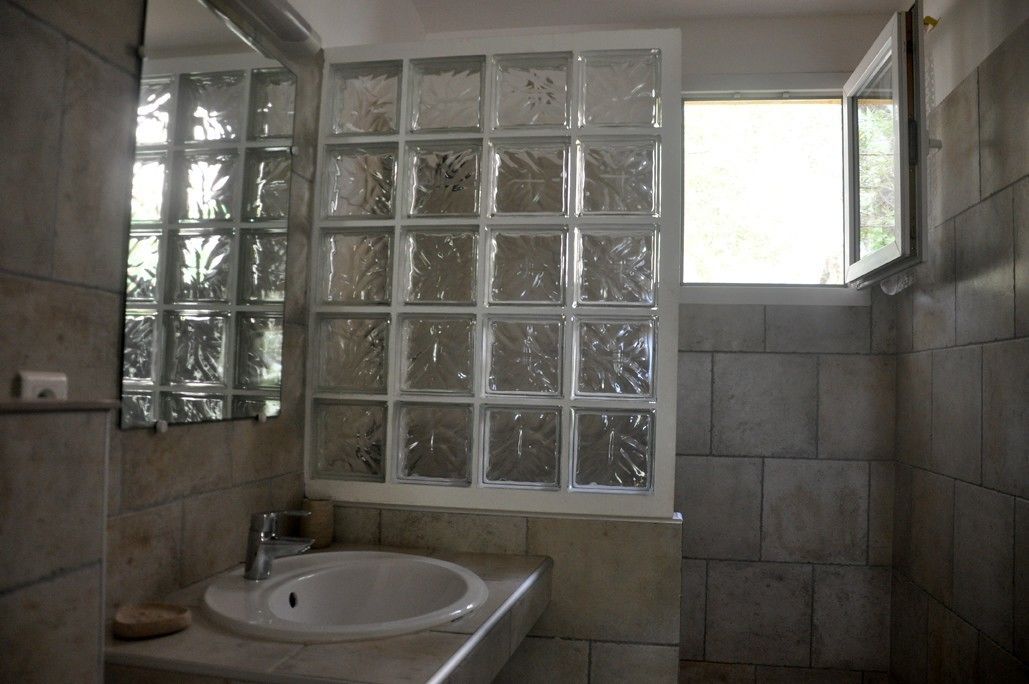 Une salle de bain avec une grande fenêtre, un lavabo et des murs carrelés.