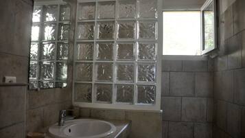 Une salle de bain avec une grande fenêtre, un lavabo et des murs carrelés.