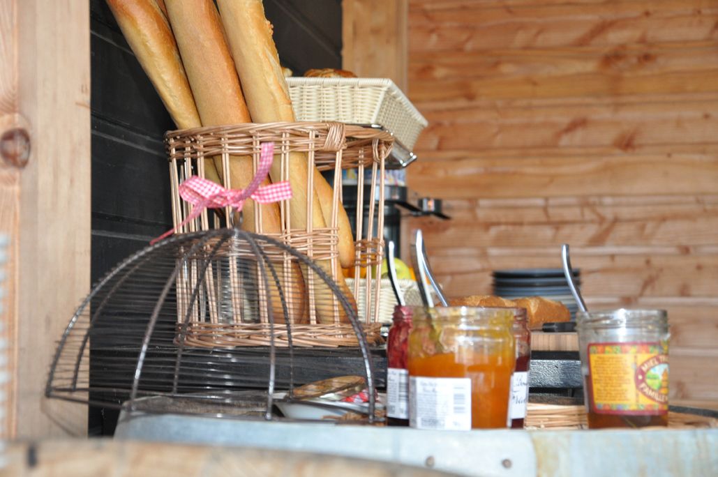 A kitchen counter with baguettes, a wicker basket, a metal rack, and jars of honey.