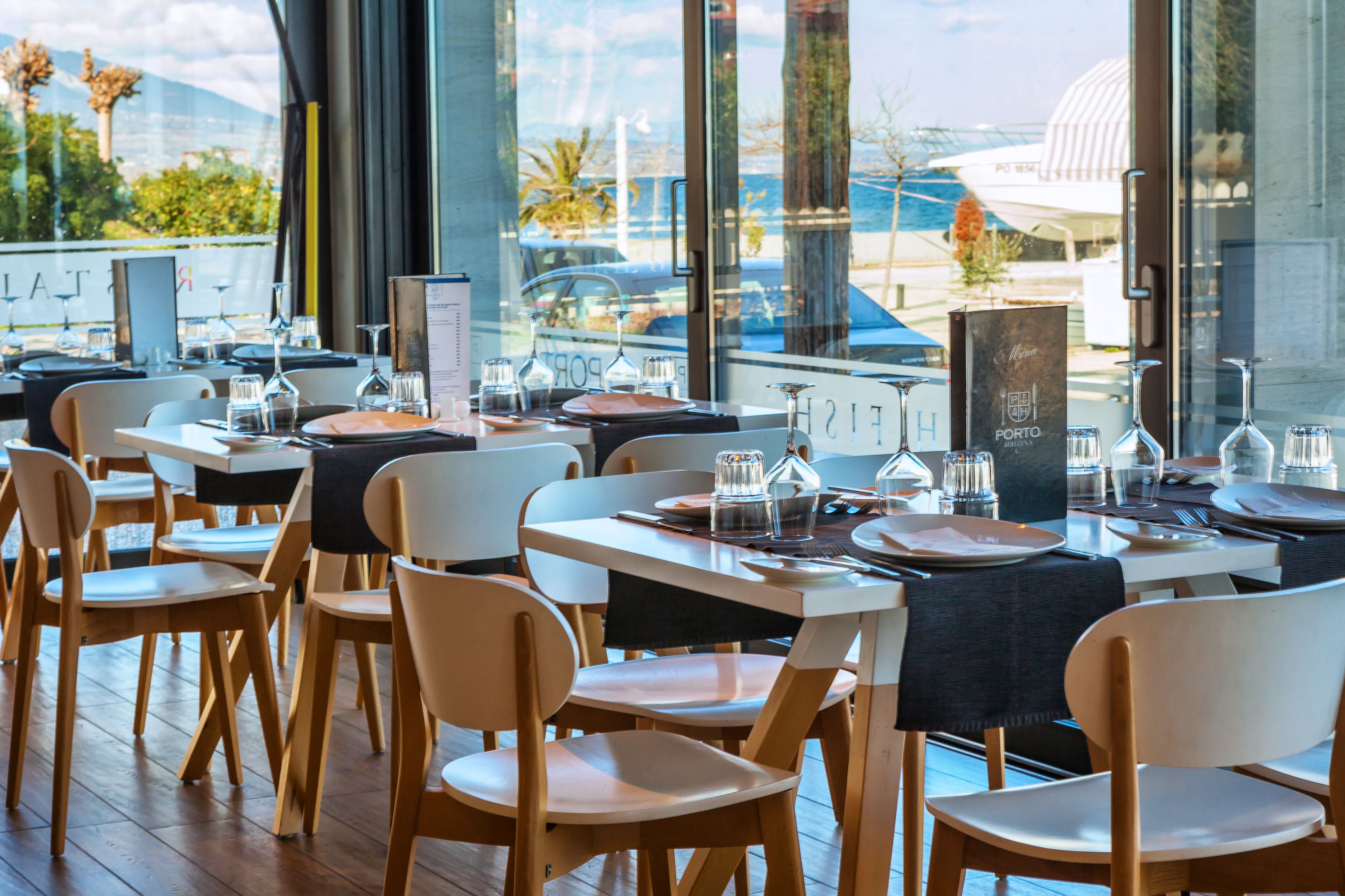 A restaurant with tables set for dining, chairs, and a menu stand.