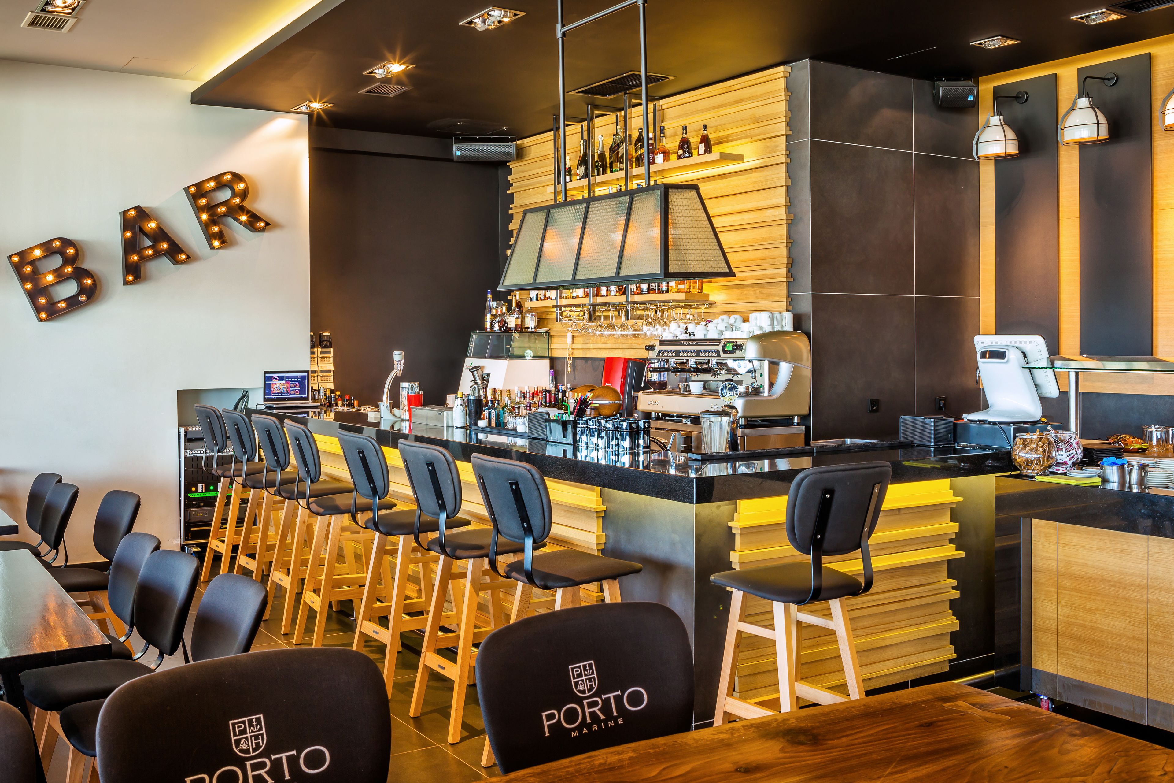 A bar area with a counter, bar stools, and a wall-mounted sign that reads "BAR".