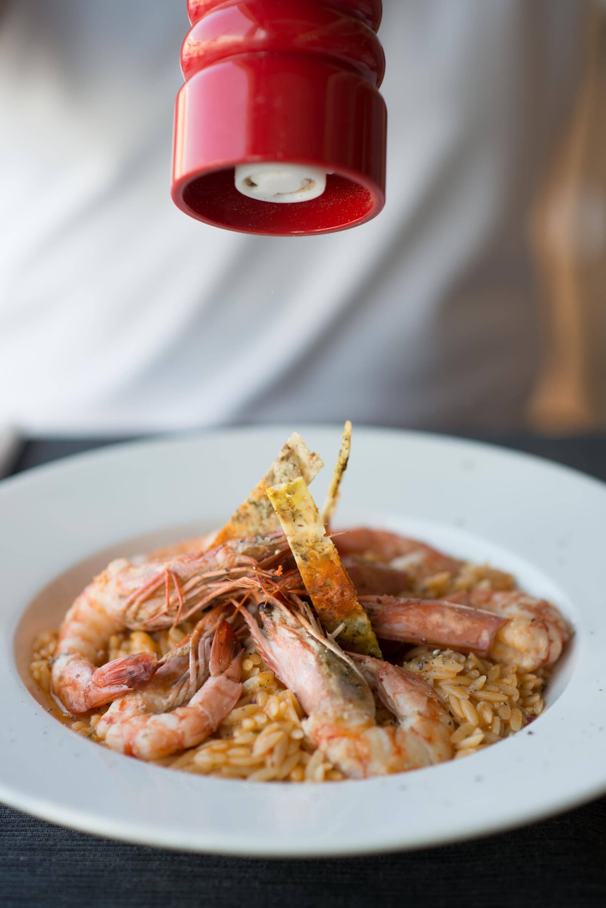 A plate of shrimp and rice garnished with a lemon wedge and a piece of bread.
