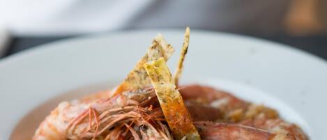 A plate of shrimp and rice garnished with a lemon wedge and a piece of bread.