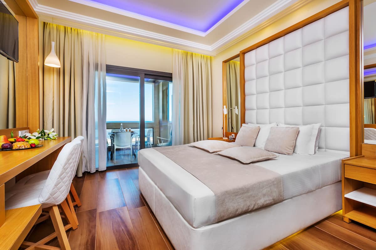 A hotel room with a large bed, a desk with a chair, and a view of the outdoors.