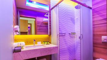 Een moderne badkamer met een marmeren wastafel, een spiegel, een douche met een golfvormige glazen deur en een houten wand.