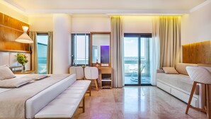 Quarto de hotel moderno com cama, escrivaninha e área de estar, apresentando uma janela grande e varanda.