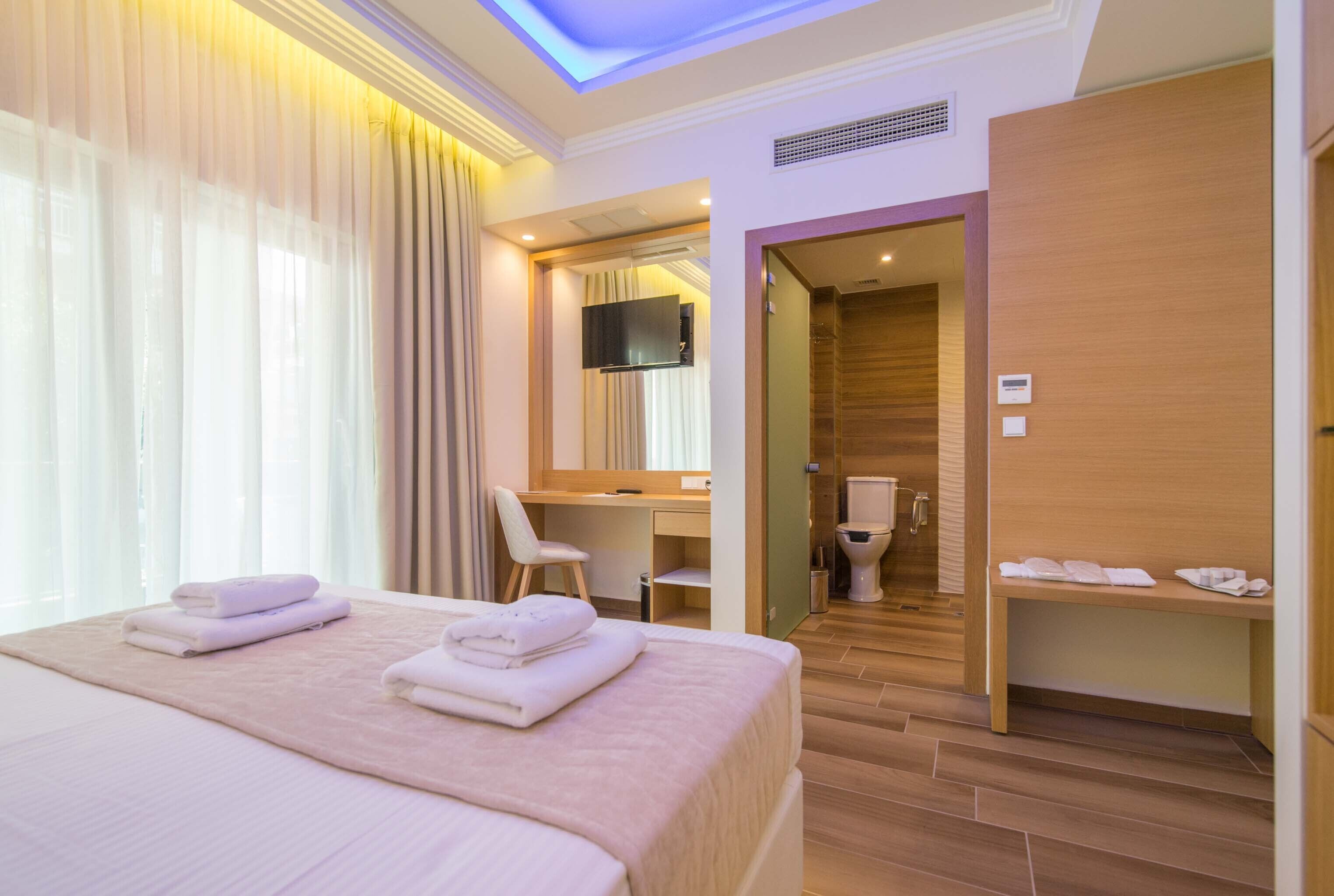 Una habitación de hotel con cama, escritorio, silla, televisión y baño.