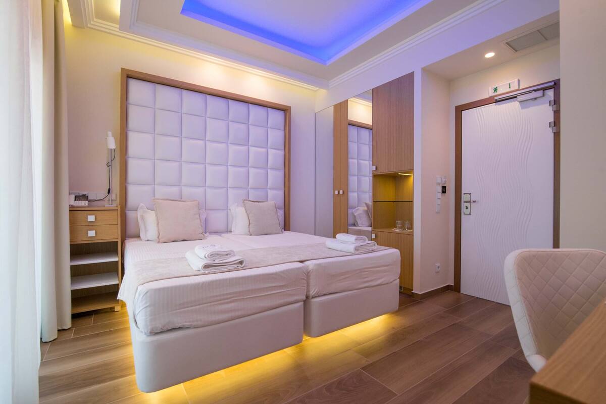 A modern bedroom with a large bed, bedside tables, a wardrobe, and a bathroom with a shower and toilet.