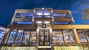 Um hotel moderno com uma entrada imponente, grandes janelas e uma placa com a inscrição 'PORTO MARINE HOTEL'.
