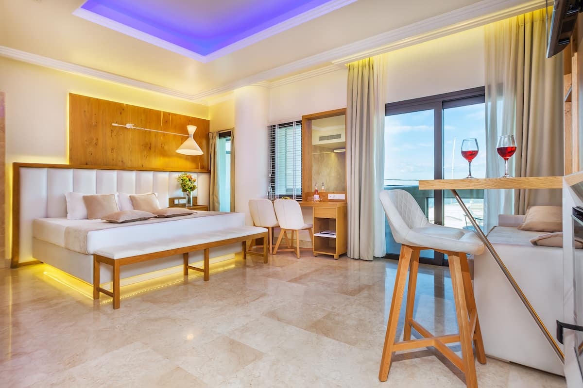 A modern hotel room with a large bed, a desk, and a bar area.