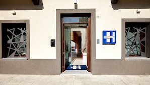 Ein Hotel mit modernem Design, darunter eine Glastür und ein blaues Schild, das Hotelservices anzeigt.