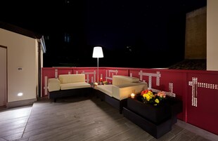Terraza en la azotea con dos sofás, una mesa y una lámpara de pie.
