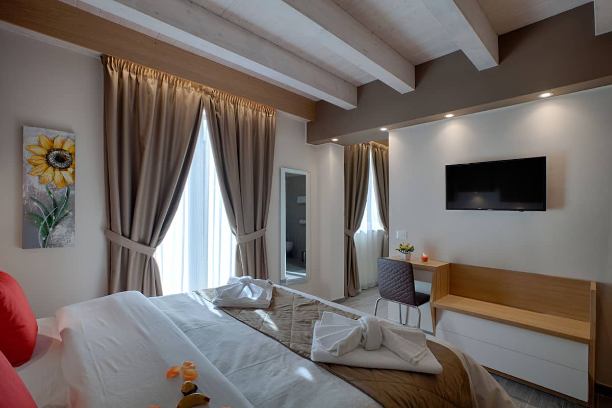 Une chambre d’hôtel avec un lit, un bureau, une chaise et un téléviseur fixé au mur.