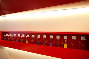 A red wall with multiple keychains hanging on hooks.