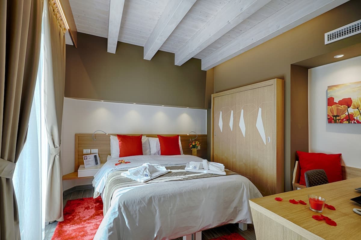 Une chambre d’hôtel avec deux lits, une tête de lit en bois, un bureau avec un verre et une moquette rouge.