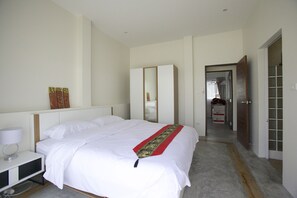 A hotel room with a large bed, a bedside table with a lamp, a wardrobe, and a mirror.