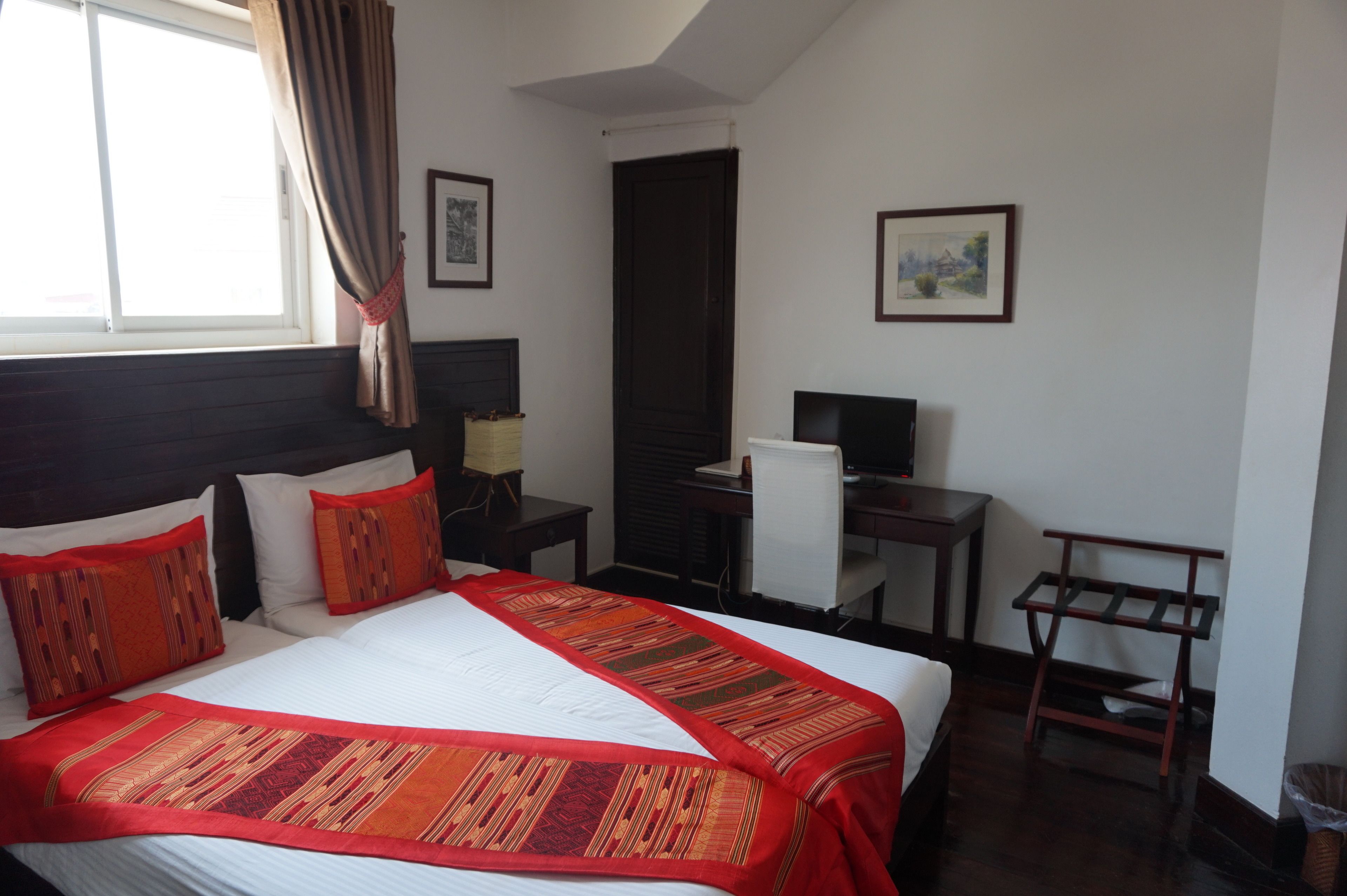 Habitación de hotel con una cama grande, un escritorio, una silla y un televisor.