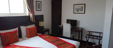Habitación de hotel con una cama grande, un escritorio, una silla y un televisor.