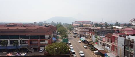A street view with buildings, parked cars, and a distant mountain.