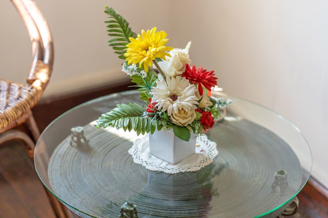 A glass table with a white vase containing a floral arrangement.