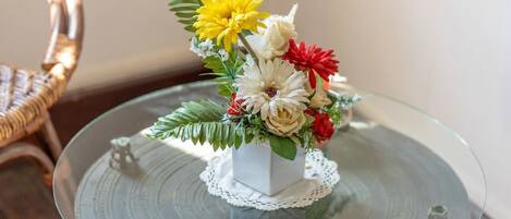 A glass table with a white vase containing a floral arrangement.