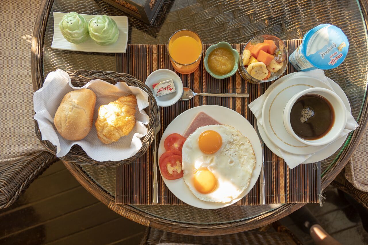Ein Frühstücksbrett mit Eiern, Toast, Obst und Kaffee auf einem gewebten Tisch.