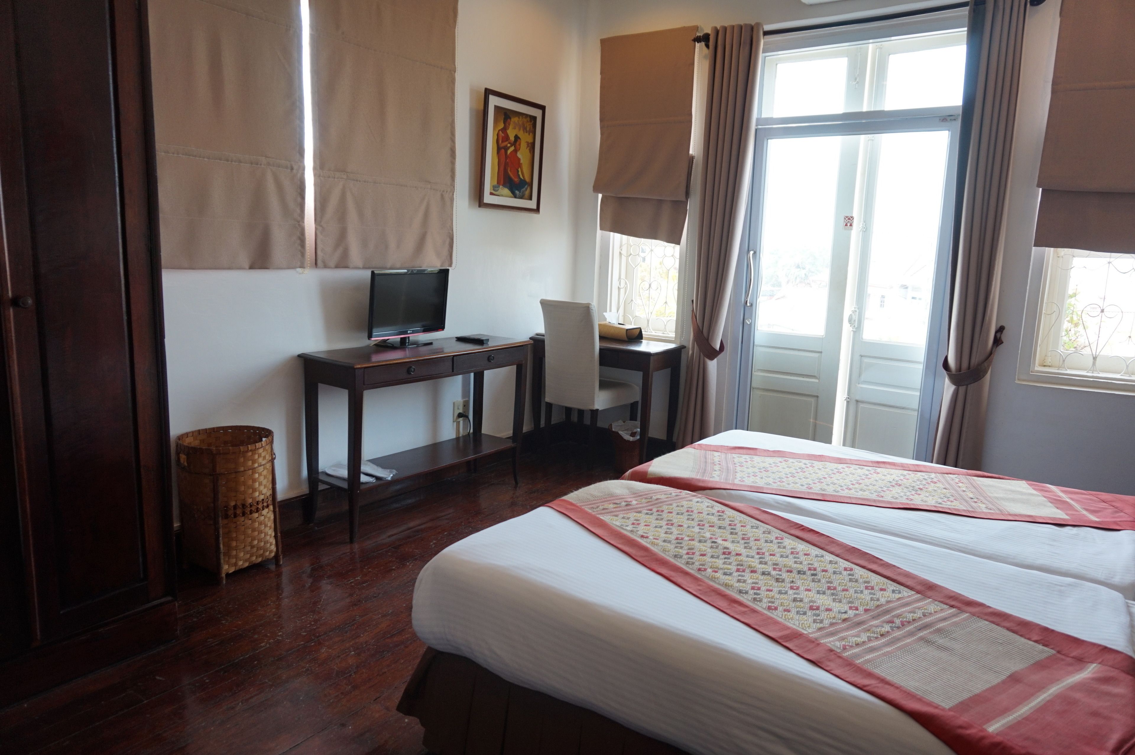 A hotel room with a bed, a desk, a chair, a television, and a window with curtains.