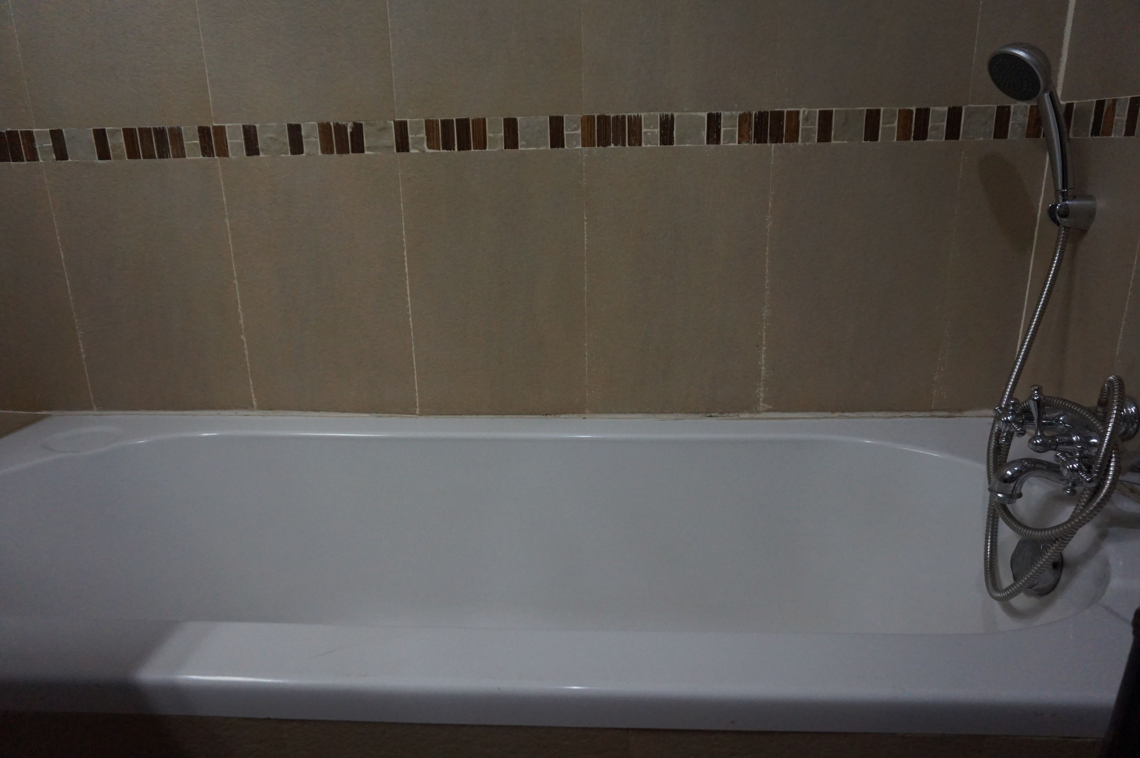 Una vasca da bagno bianca con doccetta a mano e flessibile.