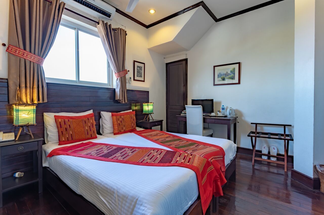 A well-lit hotel room with a large bed, bedside tables, a desk, and a chair.