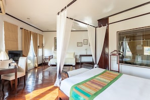 A hotel room with a large bed, a desk with a chair, a TV, and a window with curtains. - Residence Sisouk (Pakse)