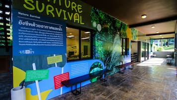 A nature-themed interior with a wall displaying 'NATURE SURVIVAL' and informational text. There are benches and a tiled floor.