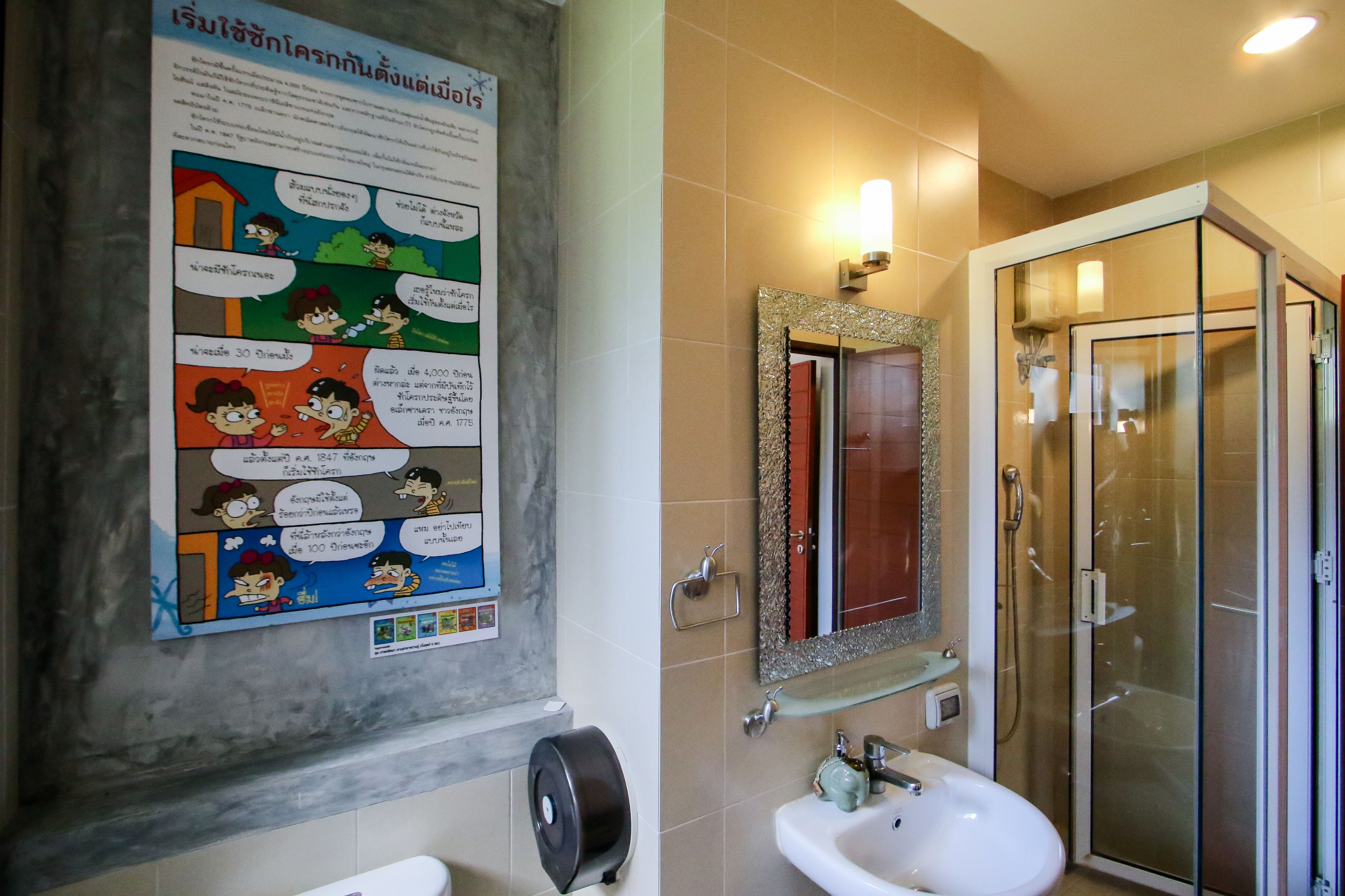Une salle de bain avec une affiche, un lavabo, un miroir et une cabine de douche en verre.