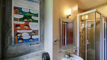 Une salle de bain avec une affiche, un lavabo, un miroir et une cabine de douche en verre.