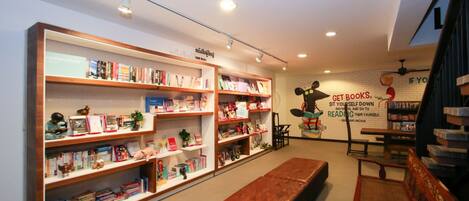 Una librería con varias estanterías llenas de libros, un banco y una pared con una cita.