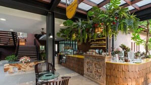Ein gemütliches Café mit Holztresen, einer Treppe und üppigem Grün.