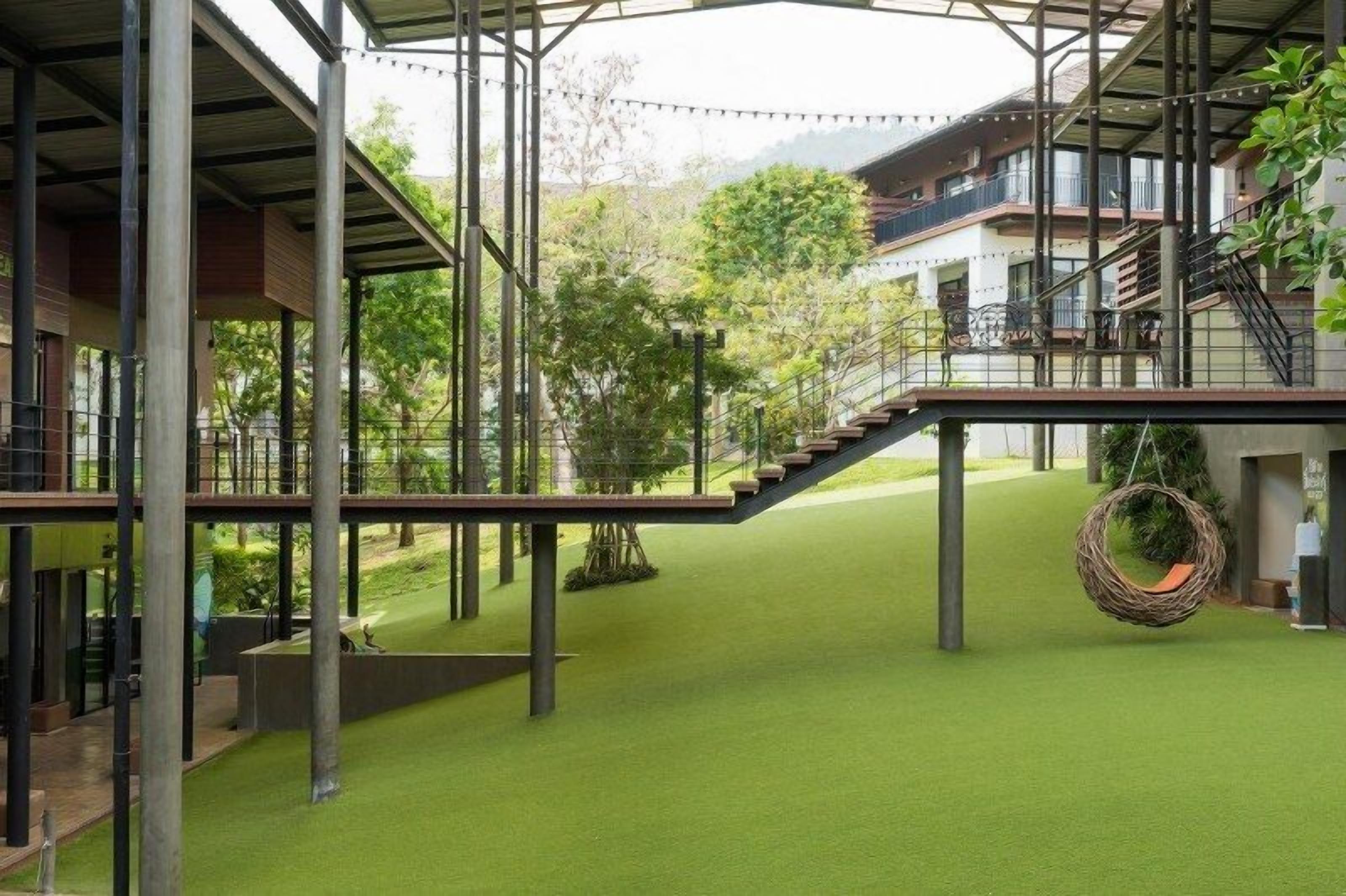 Un edificio moderno con un área exterior cubierta, una escalera y macetas colgantes.