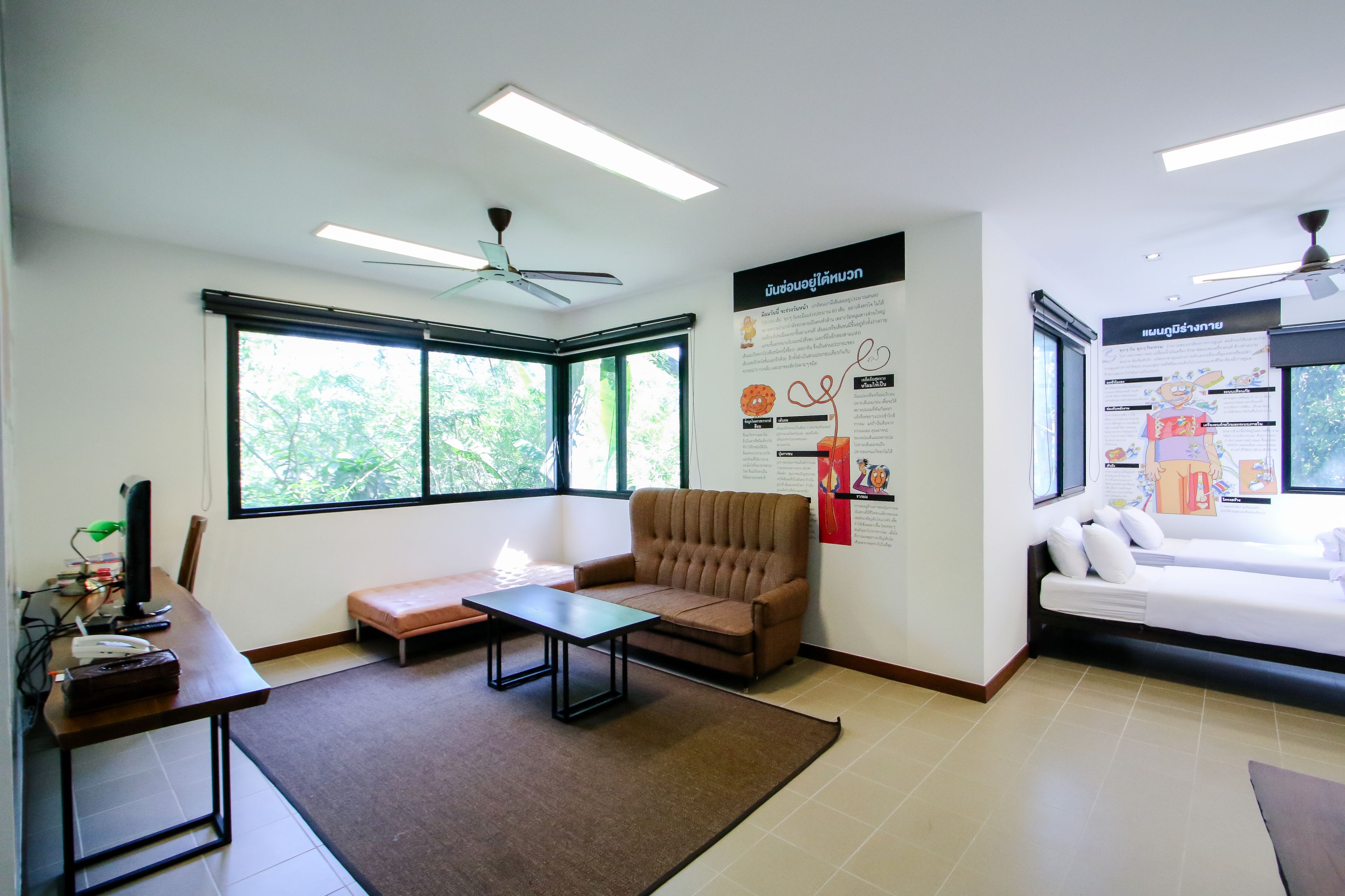 A modern room with a brown sofa, a white couch, a small table, and a standing desk with a computer.