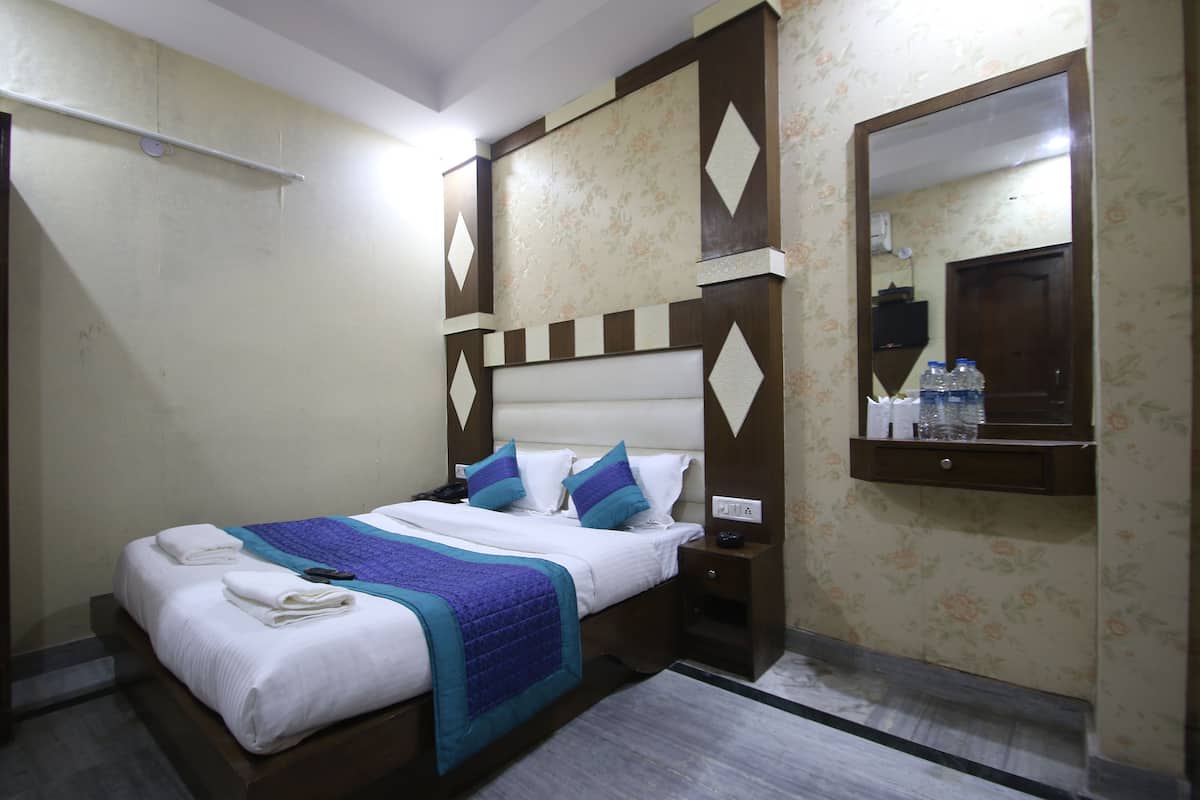 A neatly made bed with a blue and white bedspread, a wooden headboard, and a nightstand with a lamp.