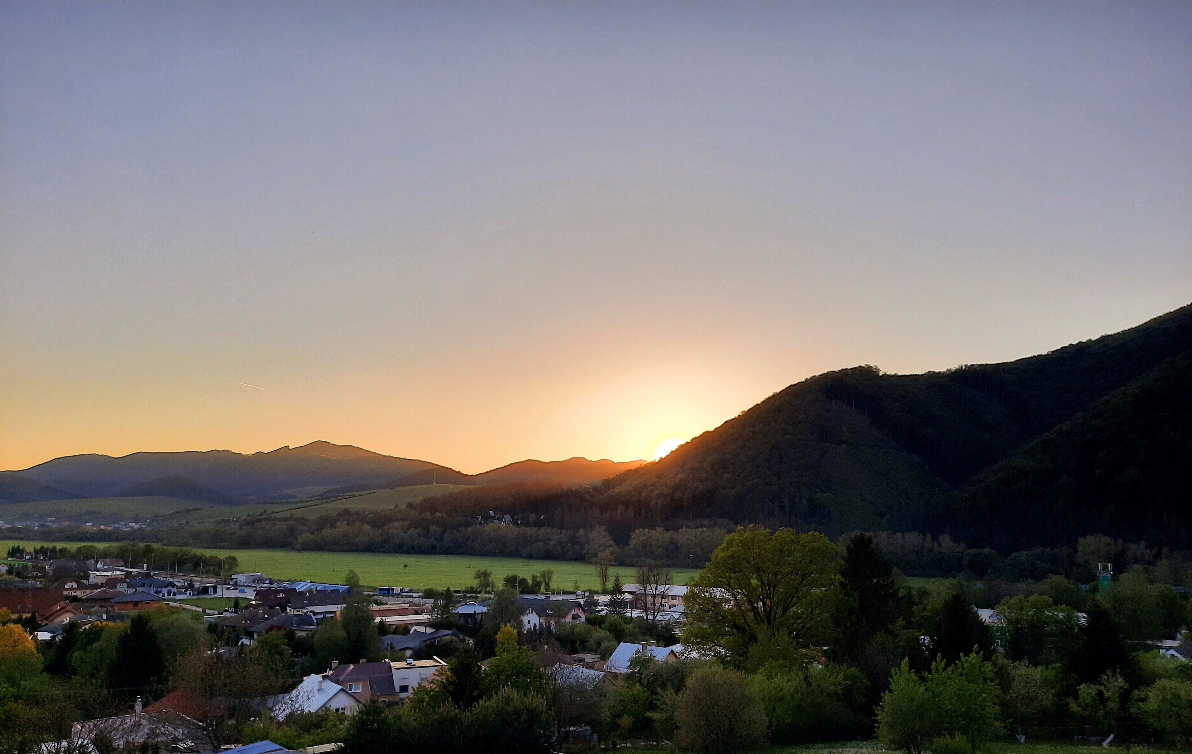 Un pueblo con vistas a las montañas al atardecer.