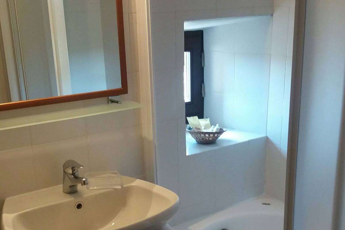 A bathroom with a sink, mirror, toilet, and bathtub.