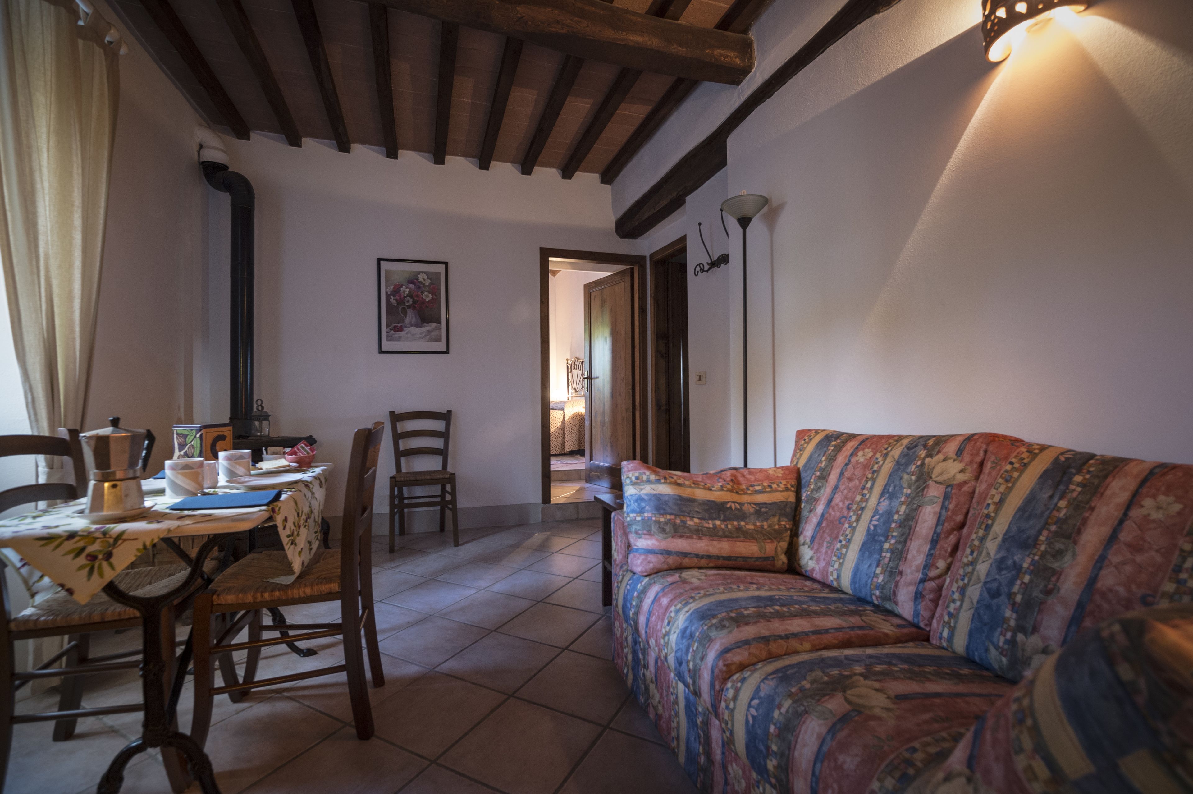 A cozy room with a dining table, chairs, a sofa, and a door leading to another room.