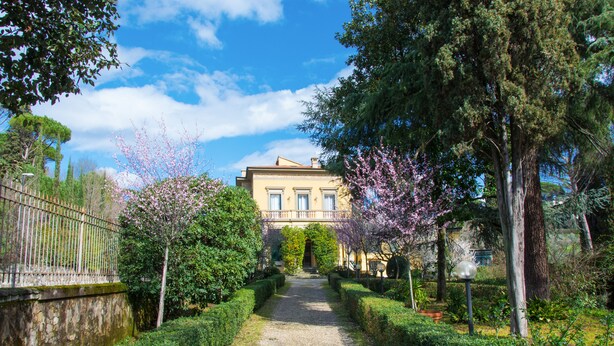 A pathway leading to a building with a symmetrical facade, surrounded by well-maintained hedges and flowering trees. - Dimora Salviati (Florence)