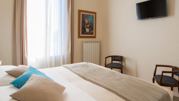 A hotel room with a large bed, two chairs, a painting on the wall, and a television. - Dimora Salviati (Florence)