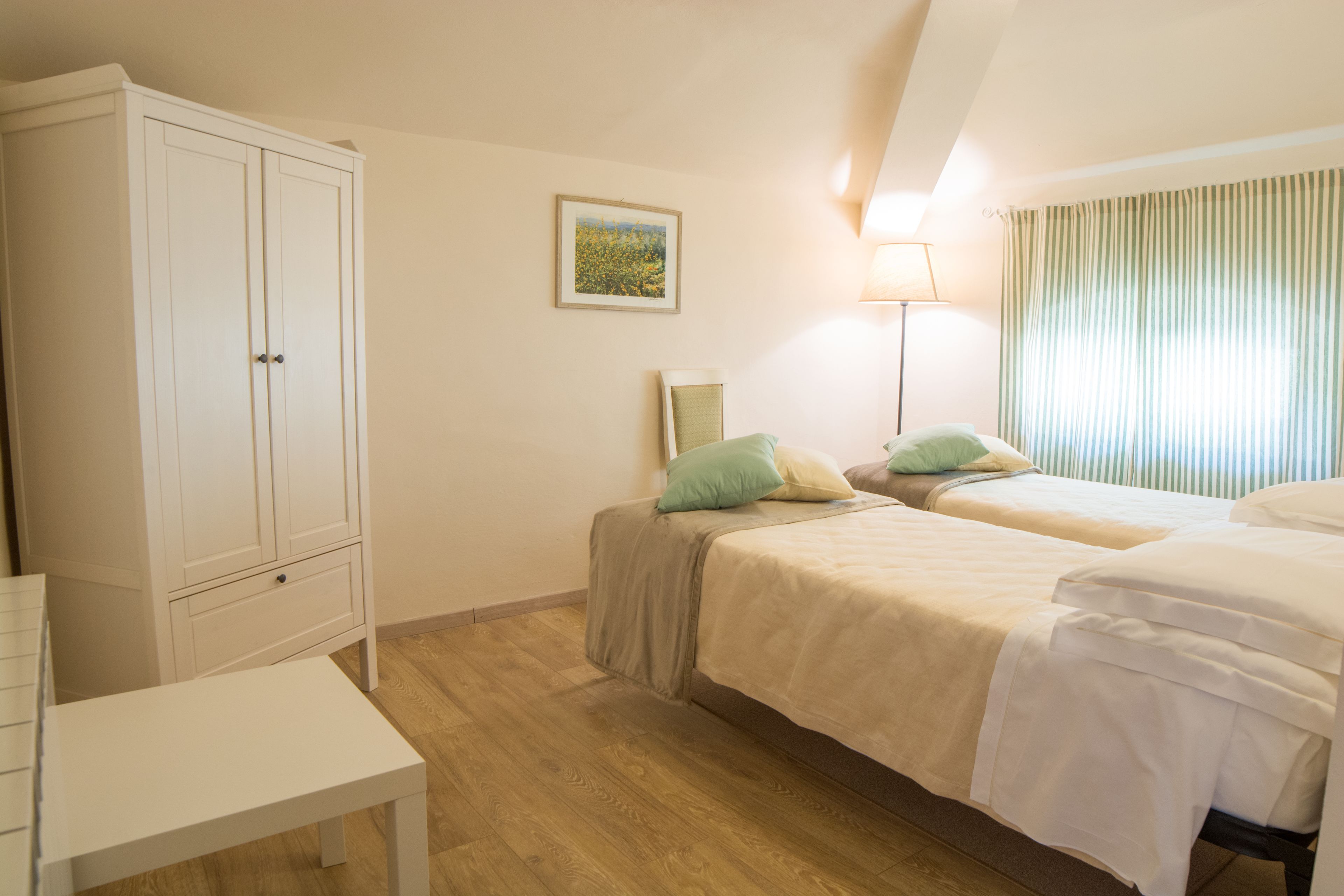 Un dormitorio con dos camas, un armario, una mesita de noche y una lámpara.
