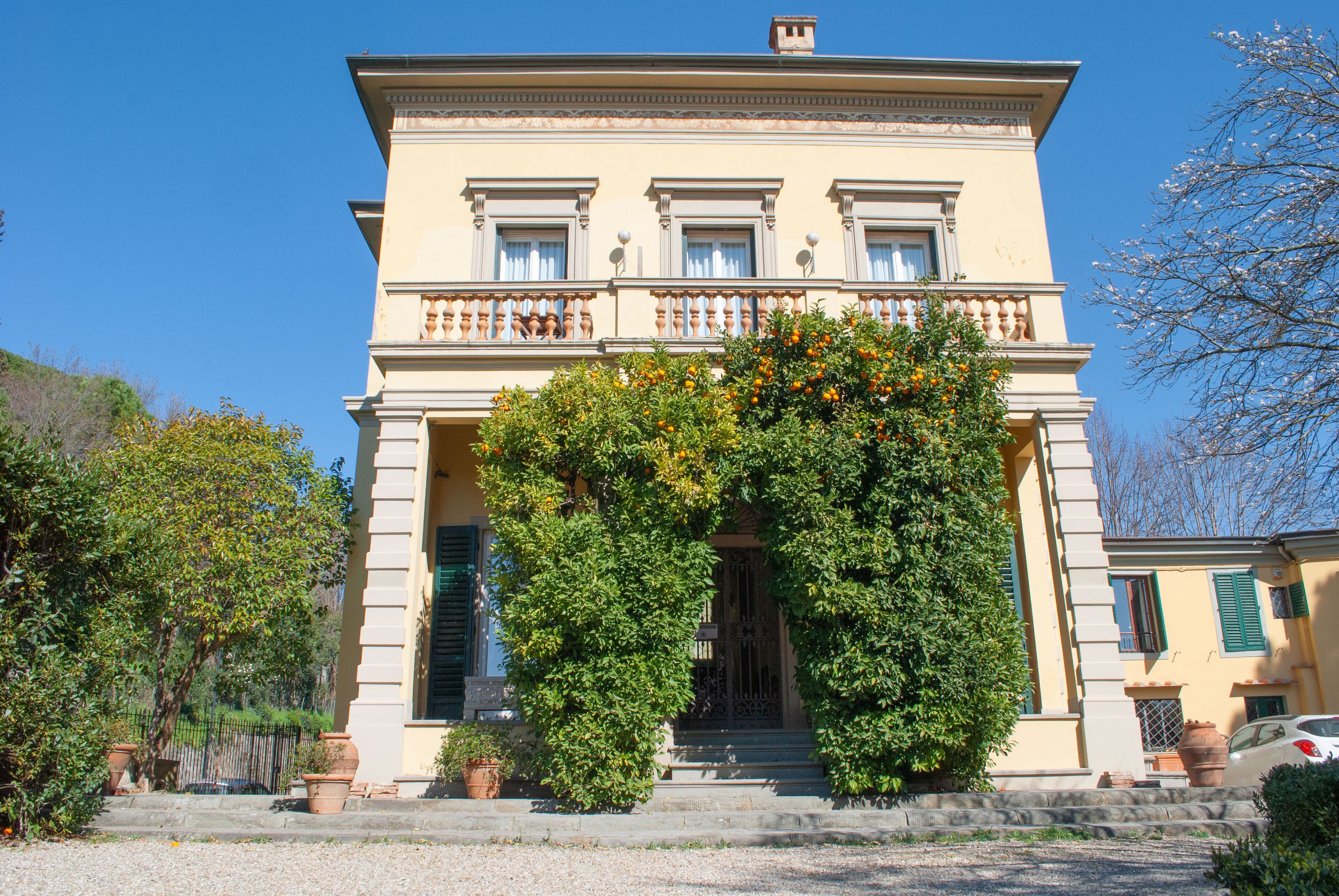 A two-story building with a symmetrical facade, a central entrance with steps, and a balcony with railings.