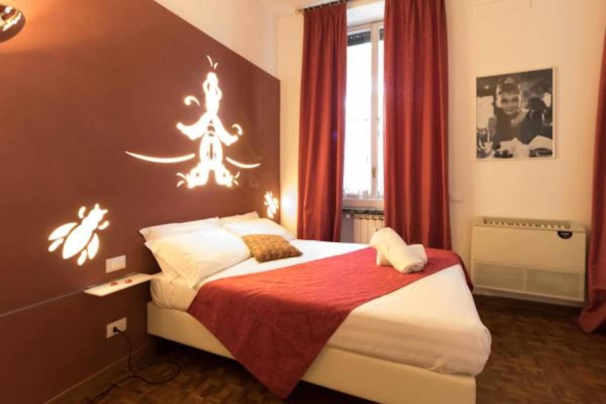 A bedroom with a bed, red curtains, a radiator, and a wall-mounted light fixture.