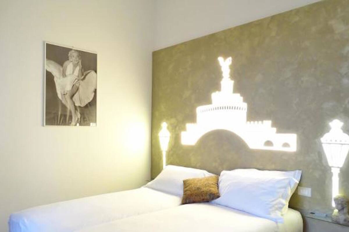 A bedroom with a bed, a wall-mounted light fixture, and a framed picture.