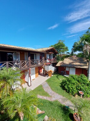 A two-story building with a balcony, a staircase, and a small garden area. - Pousada Vistacalma (Imbituba)